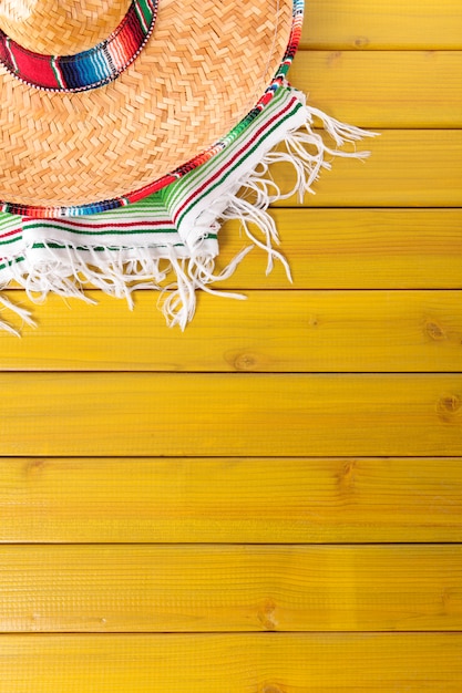 Mexican sombrero and traditional serape blanket laid on a yellow painted pine wood floor.  