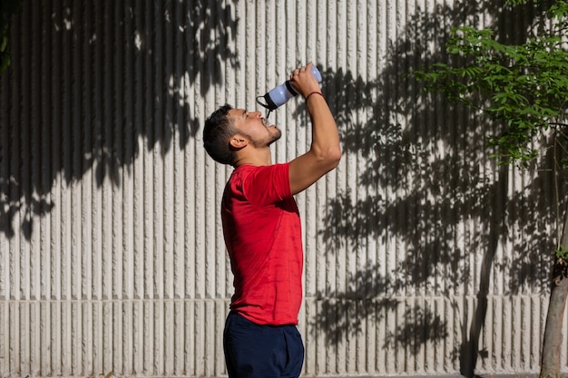 Мексиканский спортивный мужчина пьет воду