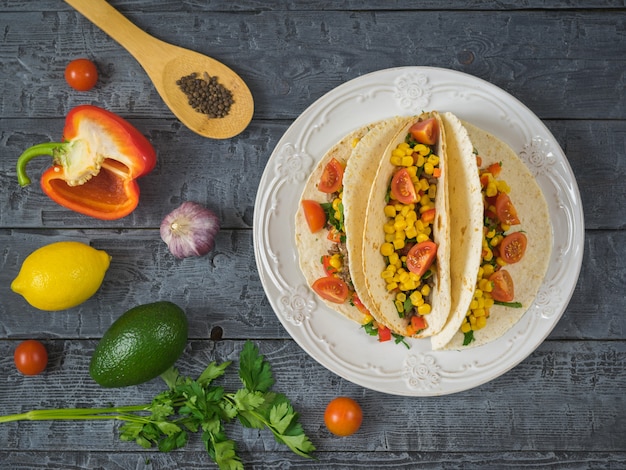 Mexican tacos on a plate on a wooden table and ingredients