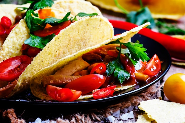 Mexican tacos stuffed with meat beans tomatoes and chili peppers selective focus