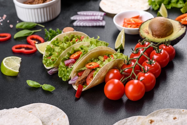 Mexican tacos with beef, tomatoes, avocado, onion and salsa sauce