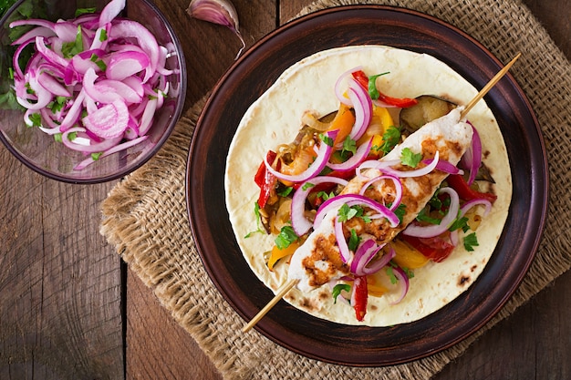 Mexican tacos with chicken, grilled vegetables and red onion.