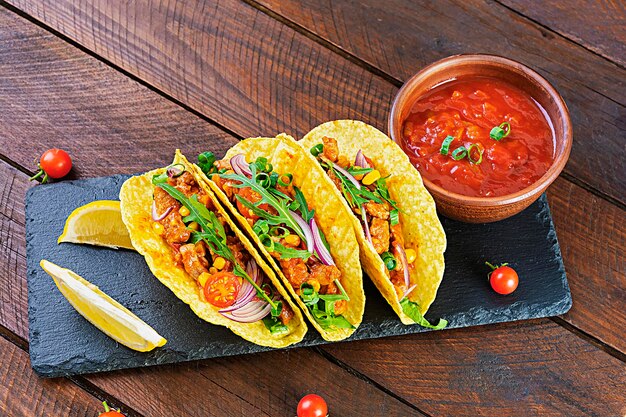 Mexican tacos with corn tortilla and meat on wooden background