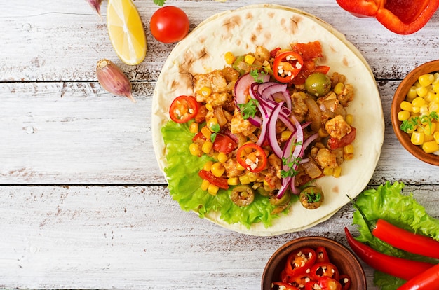 Mexican tacos with meat, corn and olives on wooden background. Top view