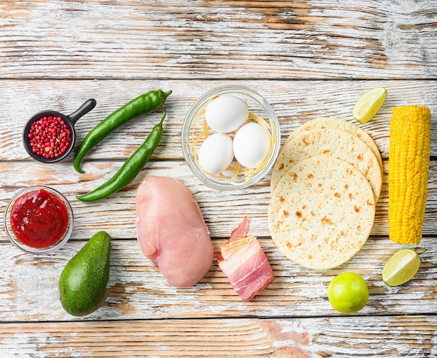 Mexican tacos with vegetables and chicken meat, corna and other ingredients over white textured wooden background , top view.