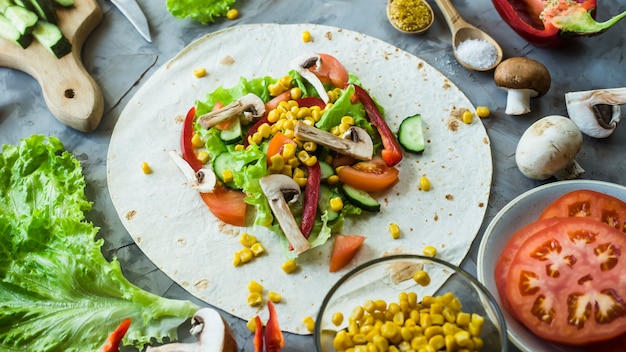 Mexican vegan burrito cooking - vegetables and mushrooms on tortillas 