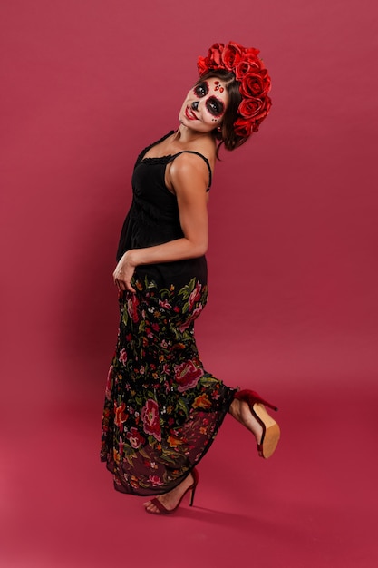 Mexican woman in dress dances at national holiday santa muerte in mask in form of skull