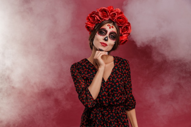 Mexican woman in la muerta attire and skull makeup during halloween with smoke