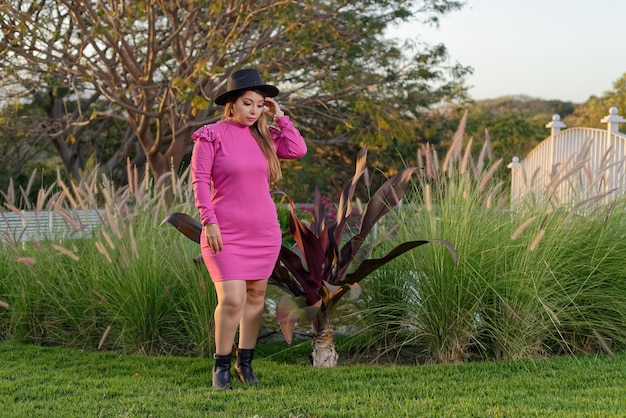 Mexican woman wearing pink dress and hat in country setting