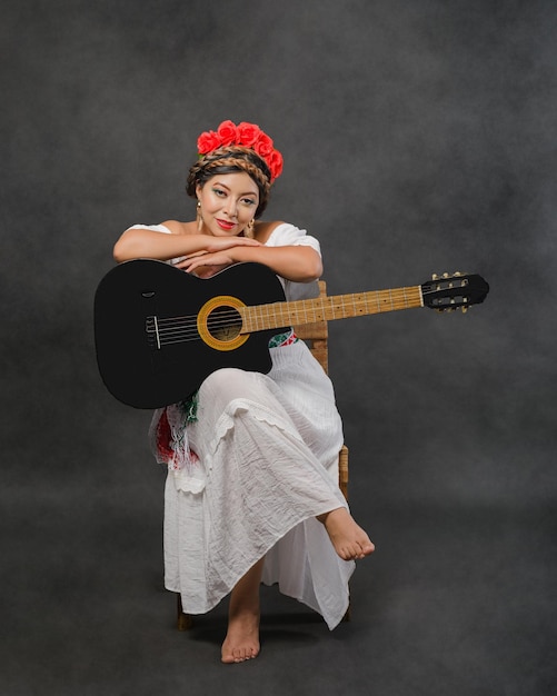 Mexican woman with guitar wearing white dress Studio portrait