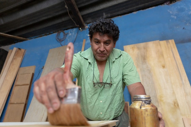 Mexican woodworker, carpenter varnishing on his workshop