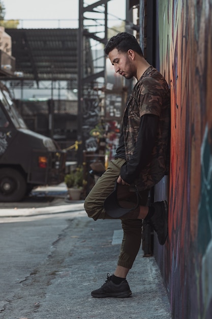 Mexican young man leaning on the wall, urban portrait