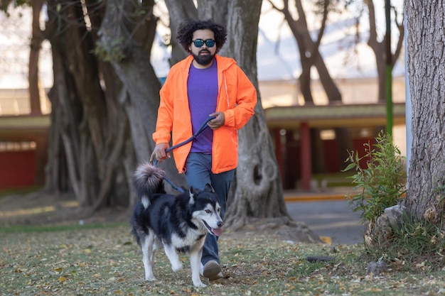 Mexican young man training husky dog in the park