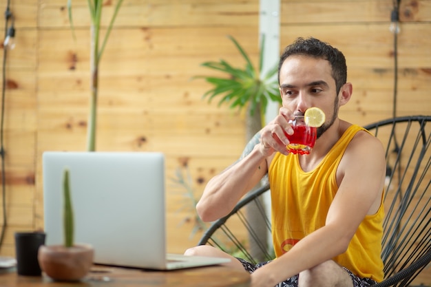 Мексиканский молодой человек, работающий на летних каникулах, пьет коктейль