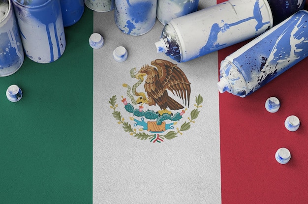 Mexico flag and few used aerosol spray cans for graffiti\
painting street art culture concept