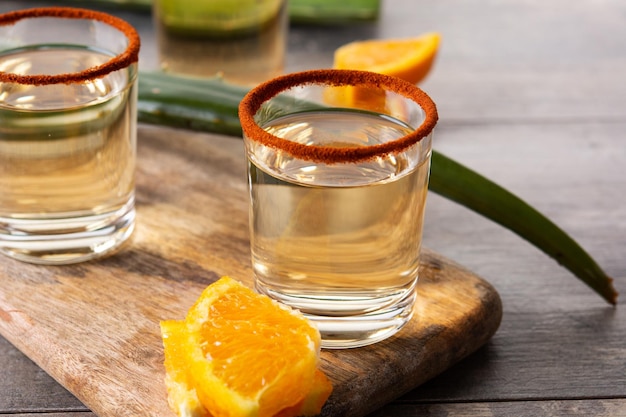 Mezcal Mexicaans drankje met stukjes sinaasappel en wormzout op houten tafel