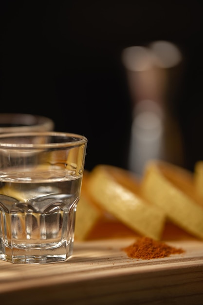 Mezcal shots met stukjes sinaasappel en wormzout op een houten bord.