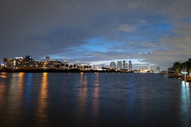 Miami-avond. Cruiseschip in de haven van Miami bij zonsondergang met meerdere luxe jachten. Nachtzicht op cruiseschepen in de buurt van de haven van Miami.