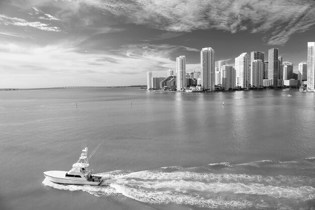 Photo miami skyscrapers with blue cloudy sky boat sail aerial view