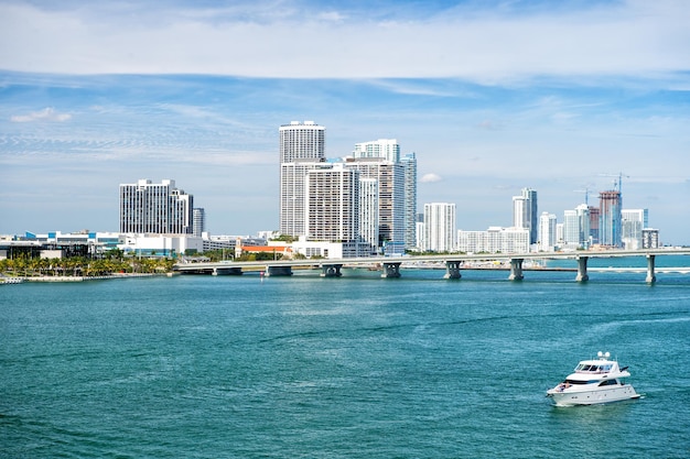 Miami skyscrapers with blue cloudy sky boat sailing next to Miami downtown and bridge Aerial view