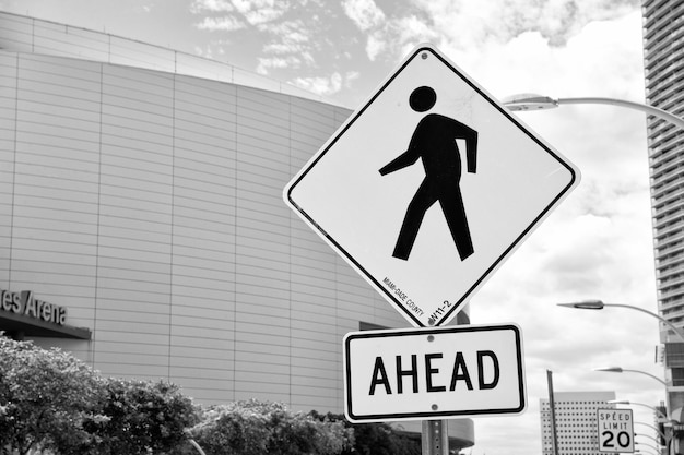 Miami USA February 29 2016 traffic sign urban background Yellow triangle sign with pedestrian symbol Indicating pedestrian crosswalk ahead Safety and traffic accident prevention