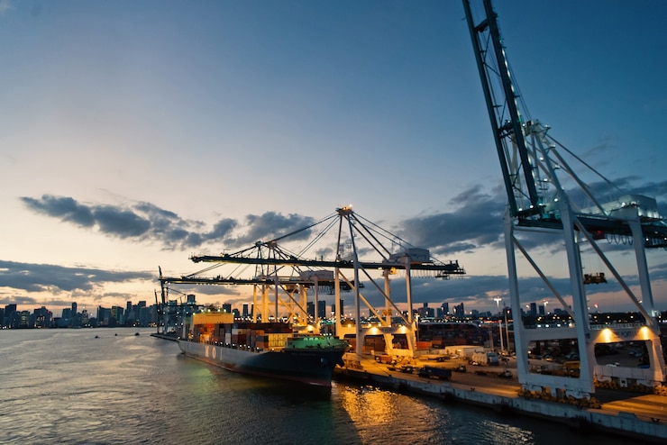 Photo miami, usa - march 01, 2016: cargo ship and cranes in sea port on evening sky. maritime container port or terminal. shipping freight and merchandise. water transport and transportation concept