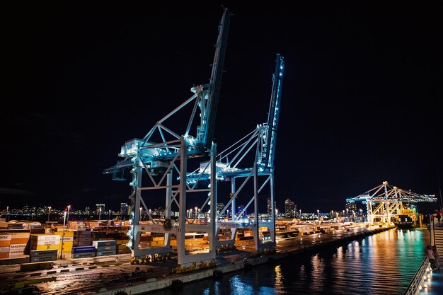 Miami, usa - 23 novembre 2015: porto marittimo con gru e cantiere navale con illuminazione notturna. spedizione, trasporto merci, merci, logistica, commercio, importazione o esportazione del concetto di consegna del trasporto