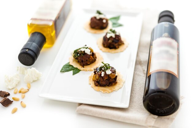 Micro bruschetta van chocolade aubergine caponata met chocolade balsamico azijn en verkruimelde hooiberg berggeitenkaas hapjes.