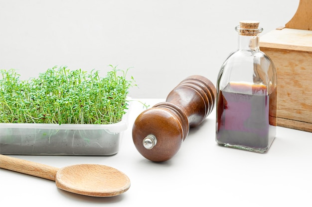 Микрозелень кресс-салат проросла дома и масло семян тыквы в бутылке на кухонном столе