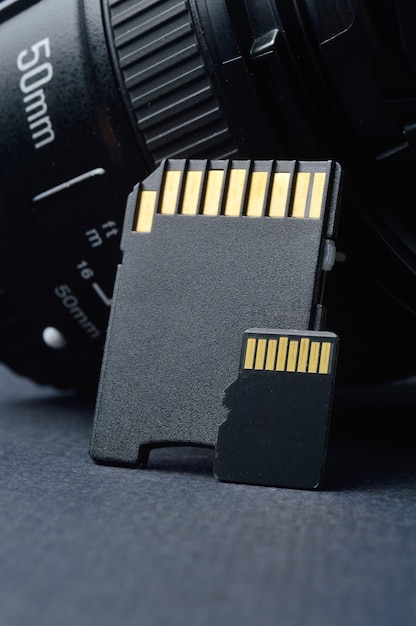 Micro sd карта с переходником на фоне сменного объектива для цифровой камеры.