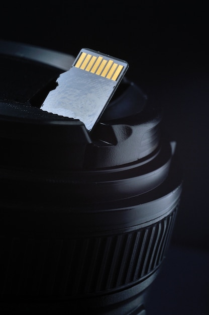 Micro sd card with adapter on the background of a replaceable lens for a digital camera.