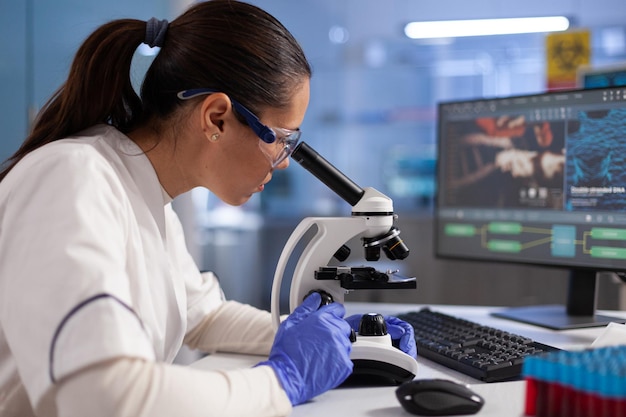 Microbiologist doctor analyzing dna sample using medical microscope during clinical experiment in hospital laboratory. Specialist researcher developing vaccine against coronavirus. Healthcare treatmen