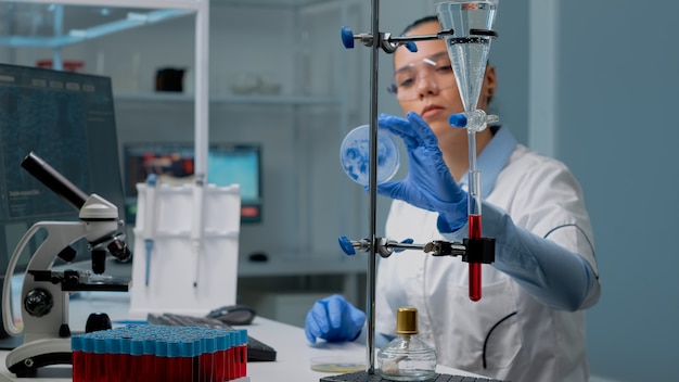 Фото Женщина-микробиолог изучает чашку петри в лаборатории