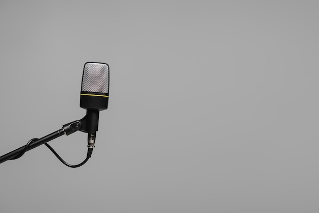Microfoon met draad op zwarte metalen stand geïsoleerd op grijs met kopie ruimte studio foto
