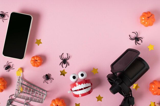 Microfoon smartphone supermarkt trolley en tanden op een roze achtergrond verkoop en online winkels voor de halloween-vakantie ruimte om te kopiëren vlakke positie bovenaanzicht