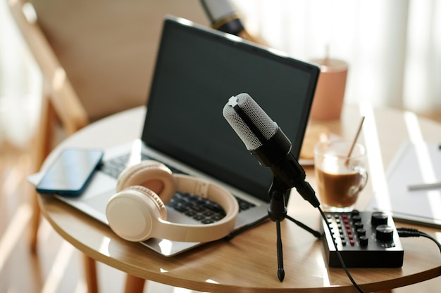 Microfoonlaptop en koptelefoon op bureau van podcaster