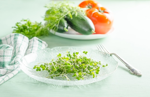 Microgreens op plaat met groenten op de achtergrond, gezond veganistisch rauwkostdieetconcept