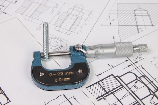 Micrometer en bouten op een achtergrond van technische tekeningen Wetenschapsmechanica en werktuigbouwkunde