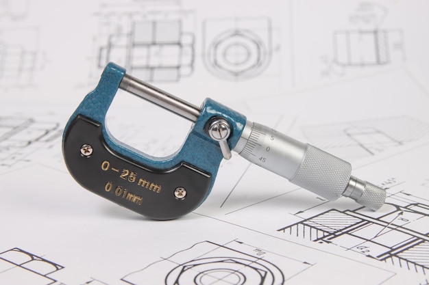 Micrometer op een achtergrond van technische tekeningen Wetenschapsmechanica en werktuigbouwkunde