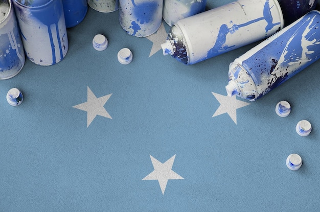 Micronesia flag and few used aerosol spray cans for graffiti\
painting street art culture concept