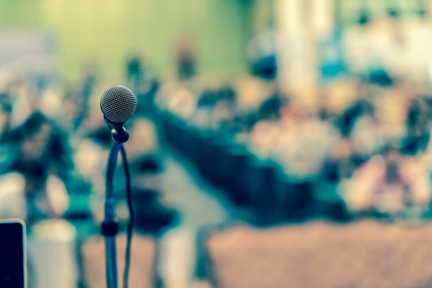 Photo microphone over the abstract blurred photo of conference hall or seminar room