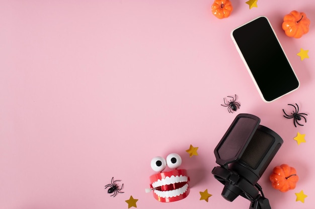 사진 호박이 있는 마이크와 스마트폰, 분홍색 배경에 이빨이 있는 시계 장난감
