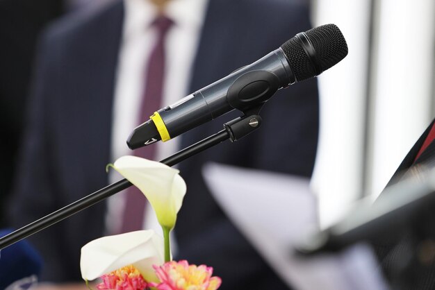 Microphone in focus against blurred unrecognizable business person at business conference