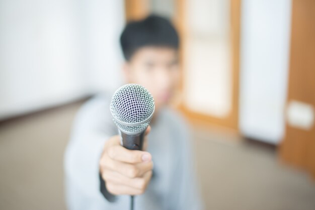 Foto microfono in una mano con sfondo sfocato di un ragazzo