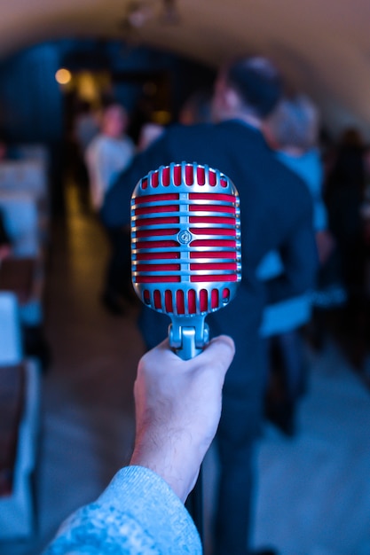 Microphone is on stage in a nightclub. Singer holds and sings into the microphone