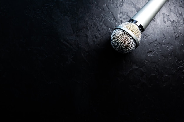 Premium Photo | Microphone lying on the black background. free time  activities at home. karaoke hobby. music concept.