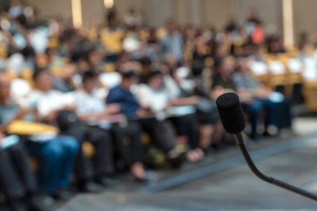 写真 会議ホールの抽象的なぼやけた写真上のマイク