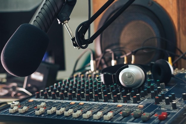 Photo microphone of the radio host in closeup with the background of the mixing console sound column and headphones radio studio