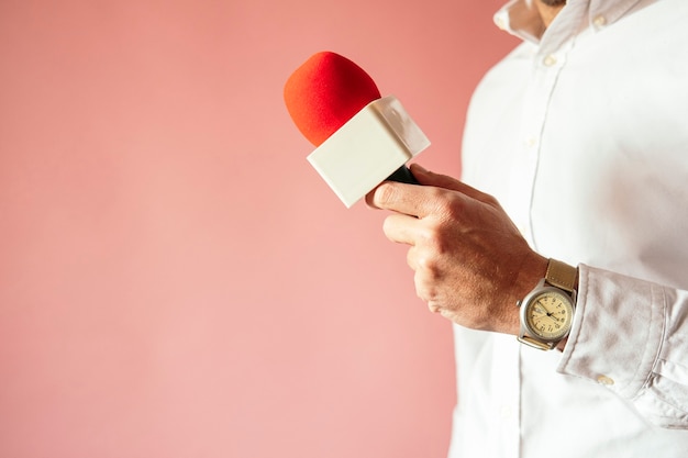 Microfono in mano al giornalista con sfondo rosa