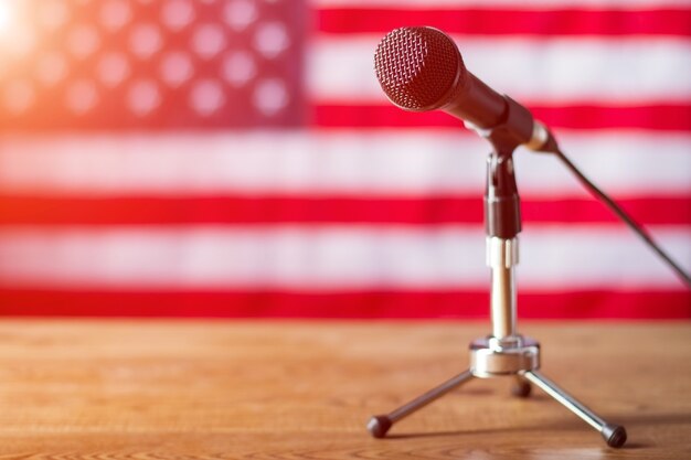 Microphone on US flag background. Table with microphone and banner. Radio show about to begin. Good morning, fellow citizens.